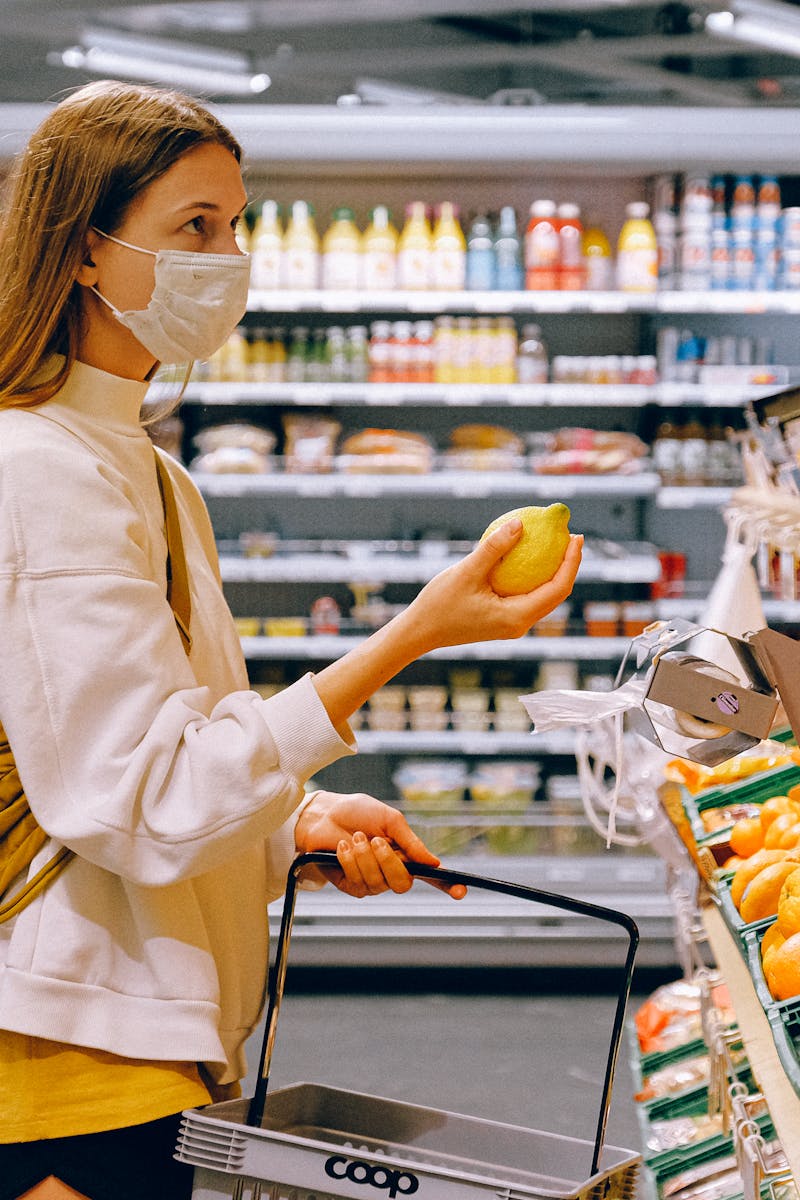 A woman wearing a face mask shops for fruits in a supermarket during a pandemic.